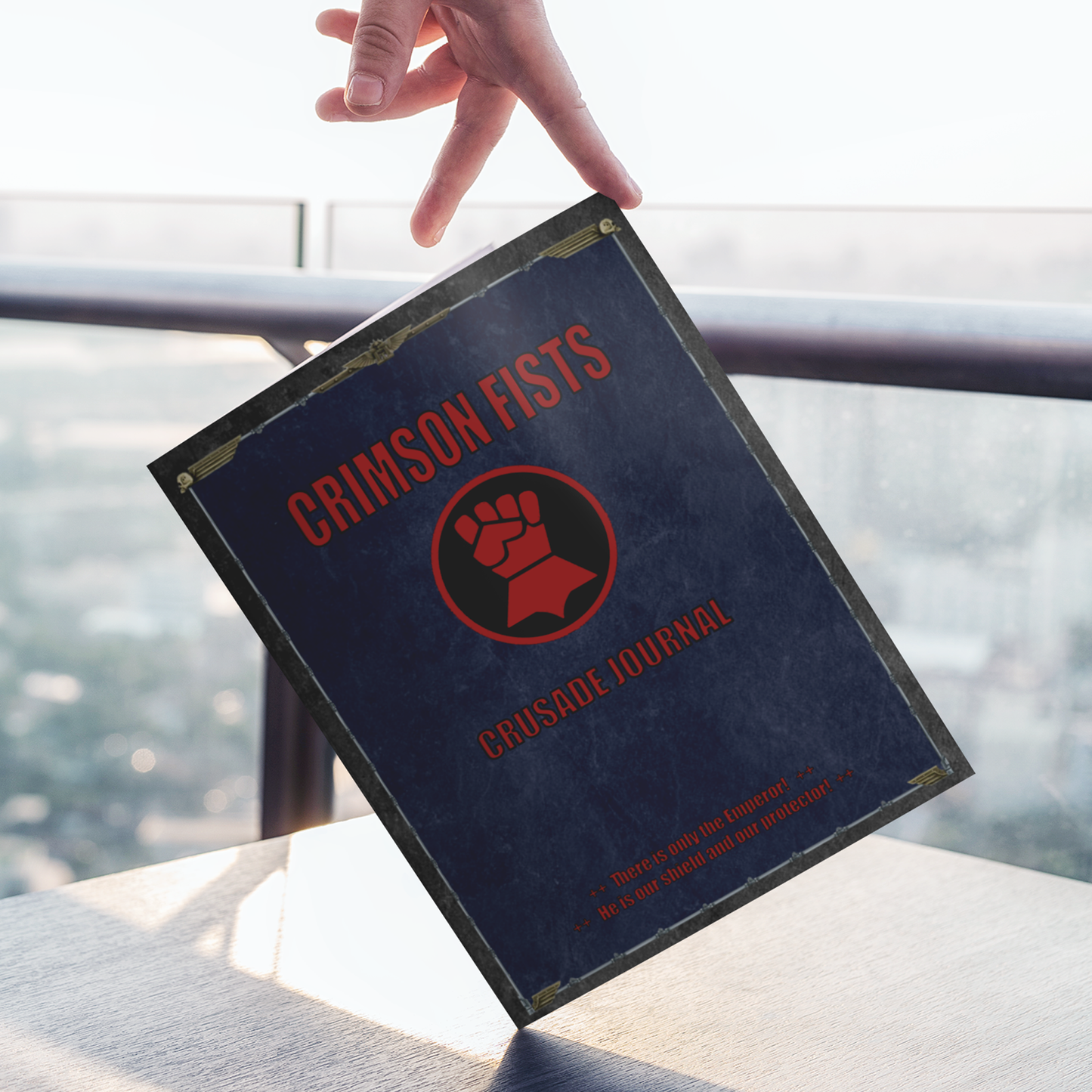 Book titled 'Crimson Fists Crusade Journal' held by a hand with a blurred background