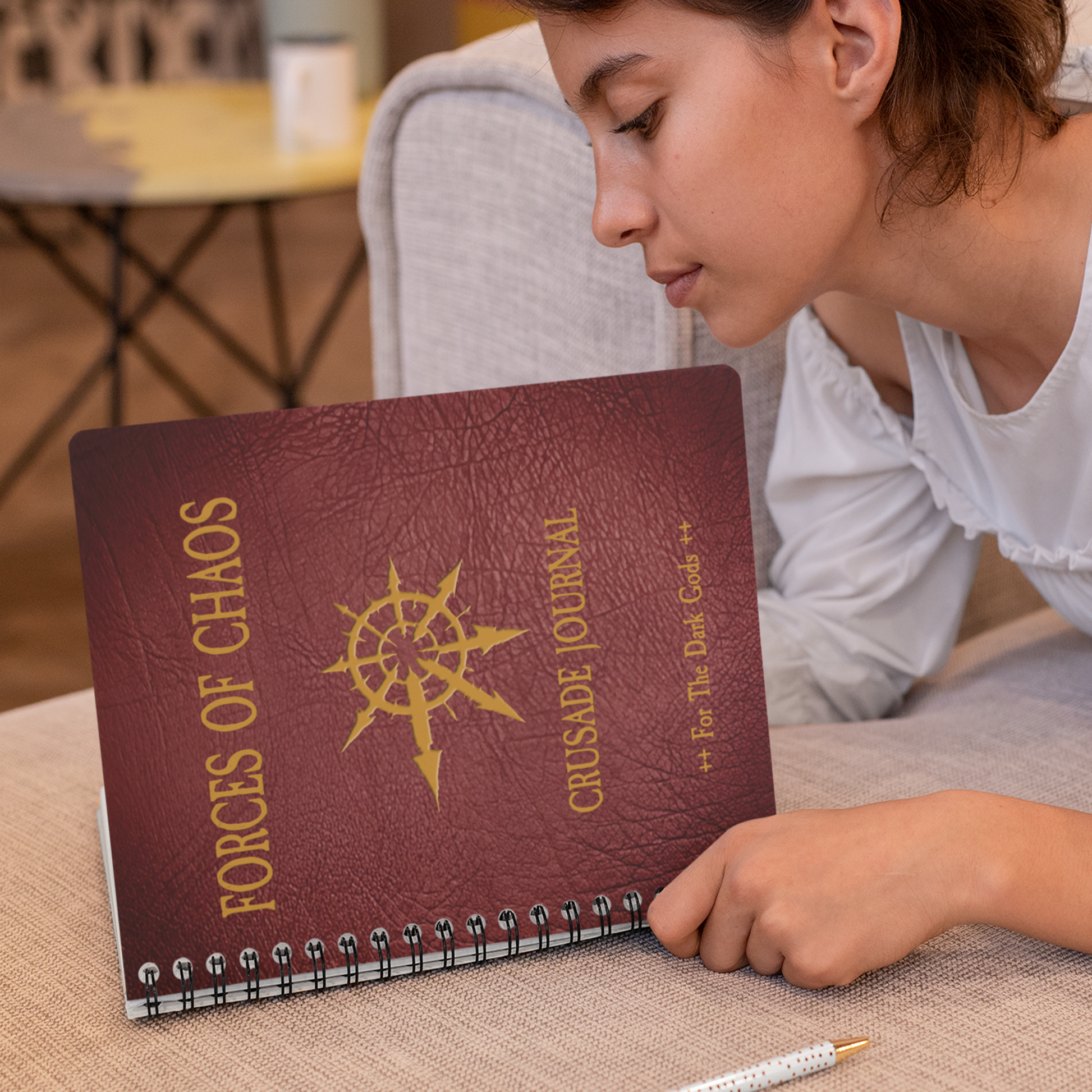 Person holding a 'Forces of Chaos Crusade Journal' on a table
