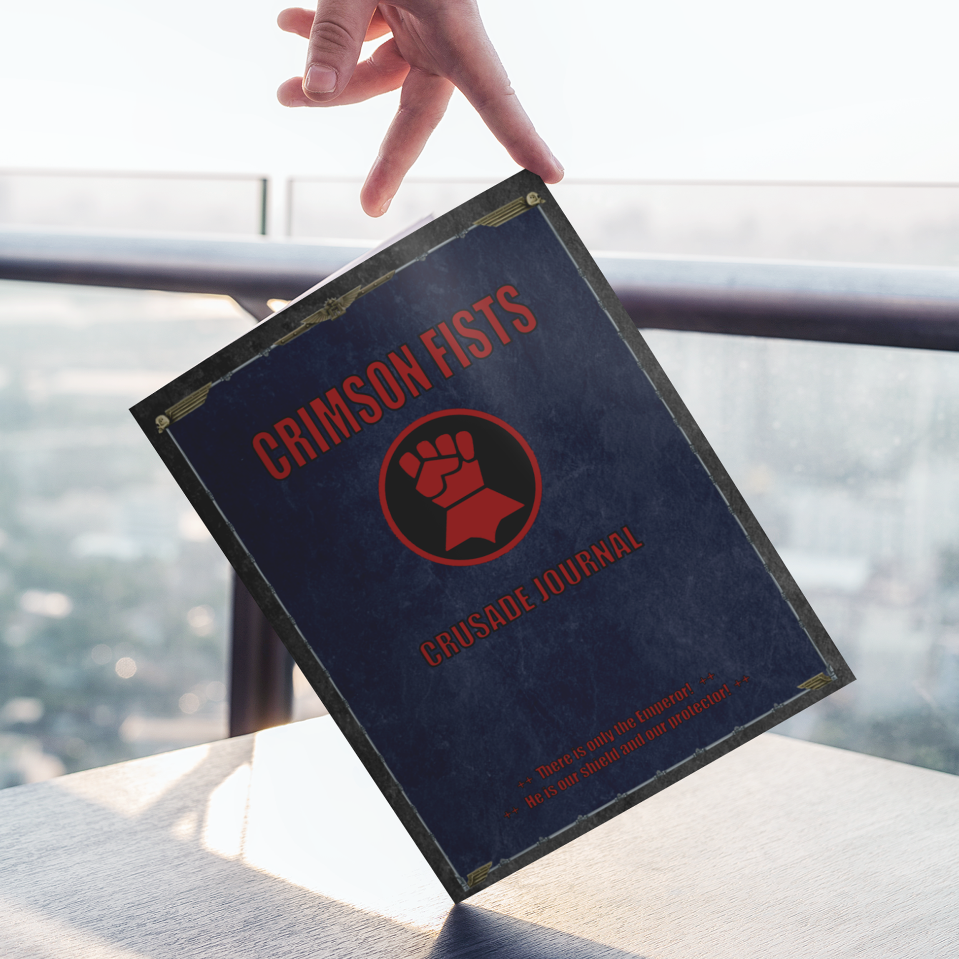 Book titled 'Crimson Fists Crusade Journal' held by a hand with a blurred background