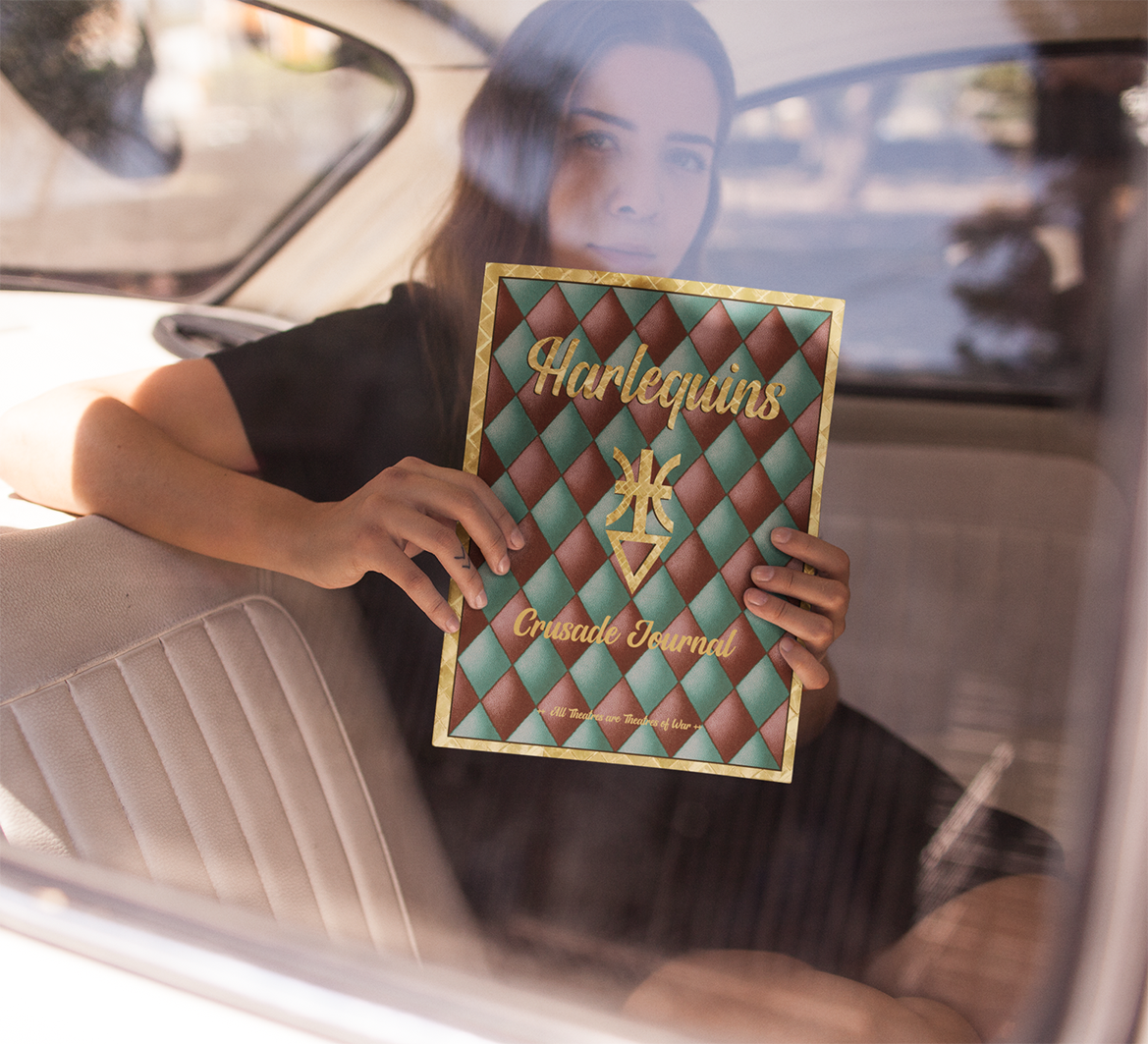 Person holding a Harlequins Crusade Journal in a car
