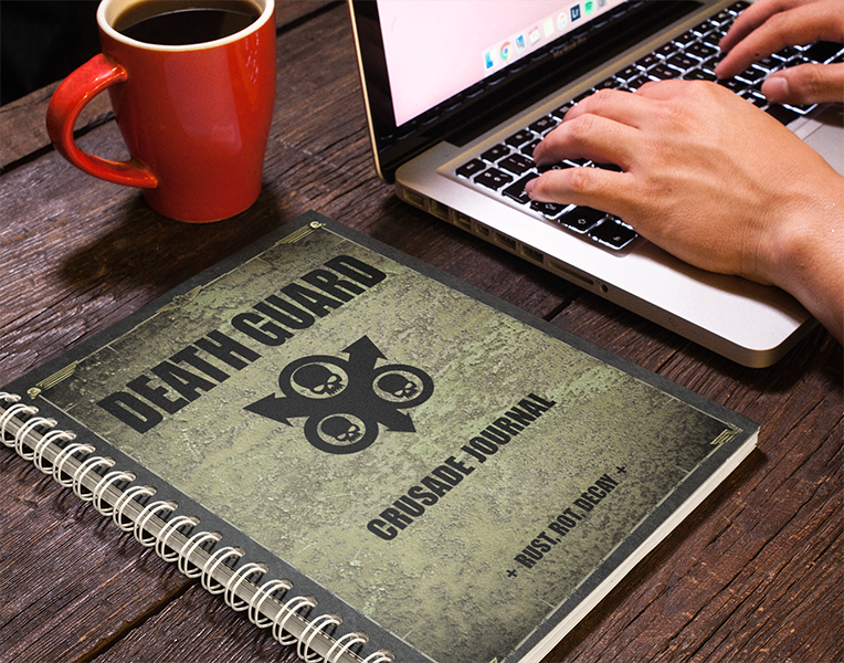 Person using a laptop with a notebook titled 'Death Guard Crusade Journal' on a wooden desk.